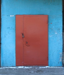 Padlocked entrance brown metal door in blue wall