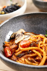 Pichi with mushrooms and creamy tomato allione in gray bowl