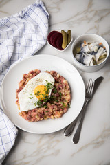Norddeutscher Hamburger Labskaus mit Rindfleisch Corned Beef, Rote Beete, Kartoffeln, Saure Gurken, Spiegelei und Rollmops auf Teller