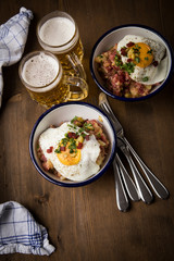 Norddeutscher Hamburger Labskaus mit Rindfleisch Corned Beef, Rote Beete, Kartoffeln, Saure Gurken, Spiegelei, Rollmops und Bier auf Holztisch
