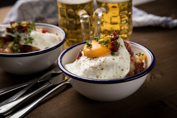 Norddeutscher Hamburger Labskaus mit Rindfleisch Corned Beef, Rote Beete, Kartoffeln, Saure Gurken, Spiegelei, Rollmops und Bier auf Holztisch