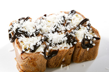 Chocolate pancake with kiwi, coconut flakes on white background top view