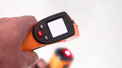 Remote electronic thermometer in hand with white screen.