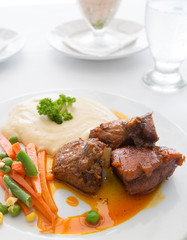 Closeup of sliced pork loin roast with potatoes and vegetables