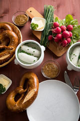Münchener Weißwurst in Terrine mit bayrischer süßen Senf, Brezel, Radieschen, Schnittlauch und Butter auf Holz Tisch