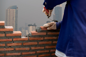 hand professional construction worker laying bricks In construction, On the background of the building, construction and masonry concept