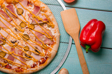 Pizza with cheese, ham, smoked chicken, mushrooms. Wooden spatula. Red pepper. Photo for the menu.