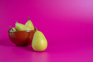 green pears in a bowl on background