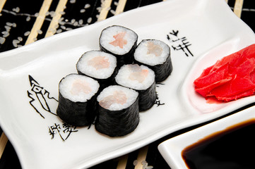 Shrimp rolls on a white plate. Red Ginger Soy sauce in a white cup. Chinese chopsticks