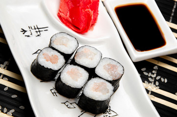 Shrimp rolls on a white plate. Red Ginger Soy sauce in a white cup. Chinese chopsticks