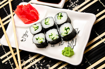 Rolls with vegetables on a white plate. Red Ginger Chinese sticks. Cup with soy sauce.