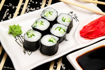 Rolls with vegetables on a white plate. Red Ginger Chinese sticks. Cup with soy sauce.
