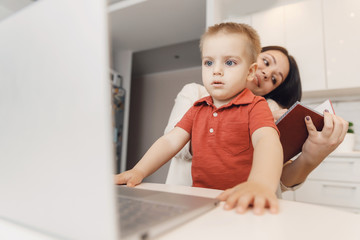 Businesswoman mother woman with kid working online computer and call phone home office