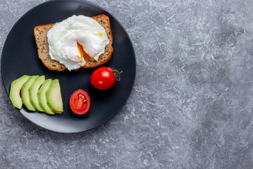 Eco breakfast with a poached egg on bread with seeds on a black plate