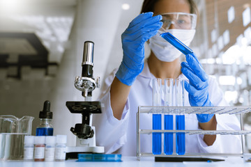scientists researching in laboratory in white lab coat, gloves analysing, looking at test tubes...
