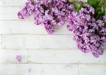 bright blooming purple lilac on a light background imitating a tree. Wooden background, branches and flowers of lilac laid out on the background. Photophone for decor