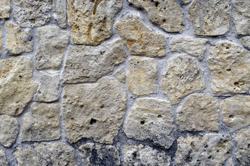The structure of the surface of rubble stone for decorative masonry with cement joints. Partially darkened stone from a fungus.