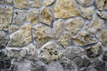 The structure of the surface of rubble stone for decorative masonry with cement joints. Partially darkened stone from a fungus.
