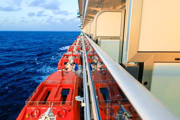 Cruise ship's side with lifeboats and balcony staterooms on a sea background