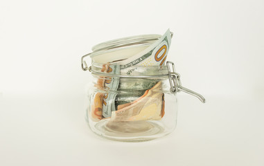 Fototapeta na wymiar Many 100 US dollars bank notes in a glass jar isolated on white background