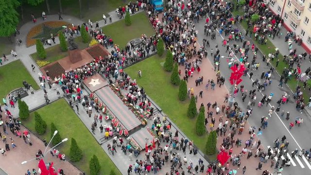 Crowd of people on a city street, top view, horizontal flight over the roofs of bright houses: Gomel, Belarus - 05/09/2019