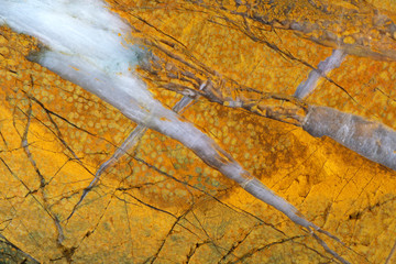 Texture of natural yellow jasper with cracks and veins of white quartz