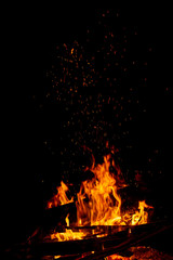 Obraz premium A campfire with a large log and rising sparks on black