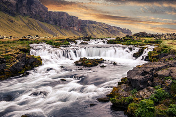 Fantastic Sunset in Iceland. Wonderful nature landscape with powerful river and waterfall. Typical Icelandic scenery