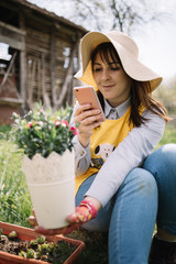 Fototapeta premium Girl holding pot with plant and taking picture