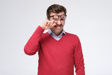 Tired caucasian man suffer from eyesight problems or blurry vision rubbing his eye.