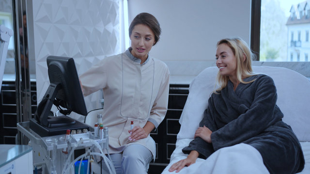 At beauty salon young woman consulting with cosmetologist examining body and face health condition before spa procedure. Cosmetology concept.