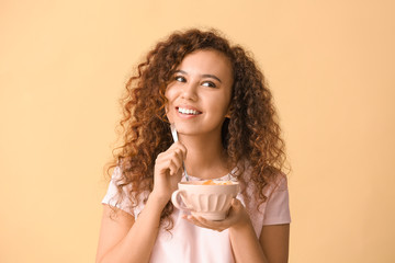 Young woman with tasty yogurt on color background