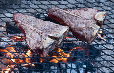 Grilling steaks on flaming grill