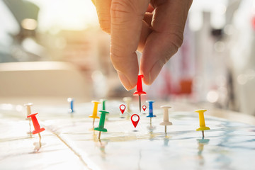 Soft focus hand holding paper pin on blur perspective road map, Red pin, point on the abstract...