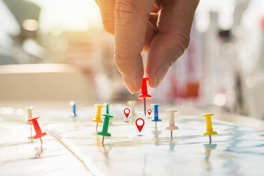 Soft focus hand holding paper pin on blur perspective road map, Red pin, point on the abstract noname map. Concept business background.