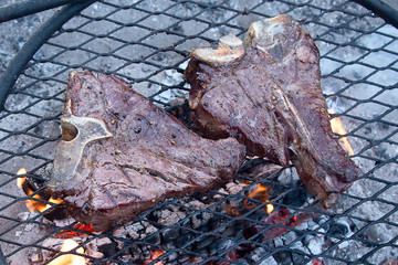 Grilling steaks on flaming grill