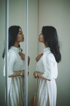Asian girl is looking herself in the mirror