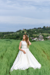 Fototapeta na wymiar Close-up portrait of a beautiful bride. Woman posing in a green wheat field.