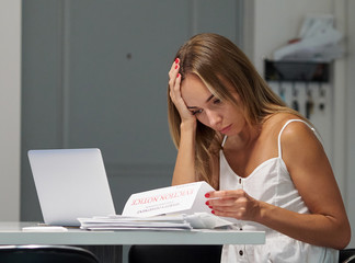 Worried female with laptop reading eviction letter in apartment