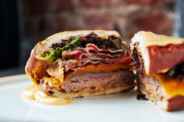 A Big selfmade Burger on a wooden plank cutted in two halves