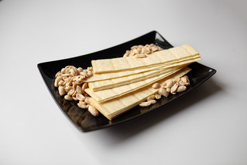 long potato chips, roasted peeled peanuts, salted beer snacks in black plate