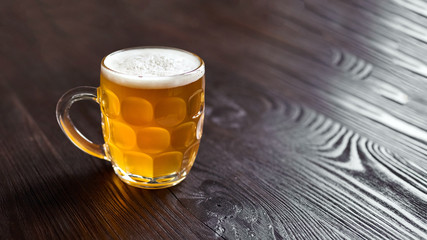 Mug of unfiltered light wheat beer on brown wooden table
