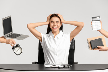Stressed young secretary with a lot of work at table on white background