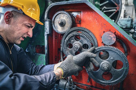 Industrial worker getting his finger stuck in the machine. Workplace accident.