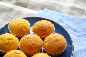 Homemade bakery. Pumpkin muffins on blue plate on table with tablecloth, selective focus. Plant-based food