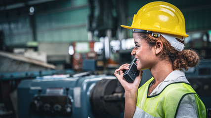 Female factory worker using handheld radio receiver for communication.	
