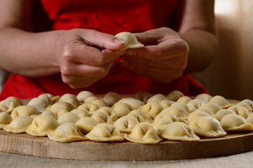 A woman makes dumplings and puts them on a cutting Board.