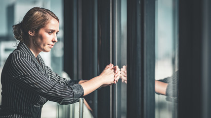 Portrait of sophisticated young successful confident CEO businesswoman looking out at the city from...