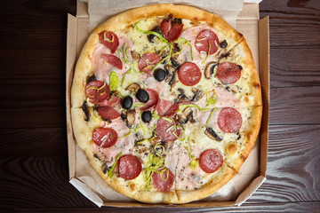 Pizza in a cardboard box on wooden table