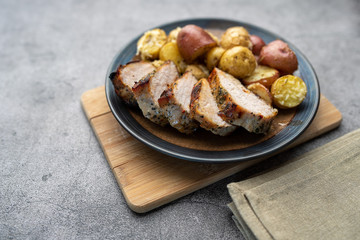 Roasted pork with spices and Parmesan roasted baby potatoes. Close up on a plate. 